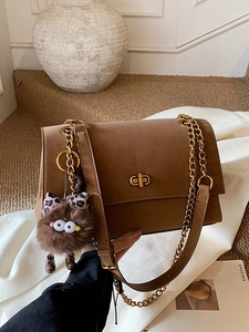 Matte brown messenger bag with gold twist lock and cute plush charm on a chain strap