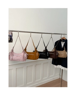 Collection of colorful suede hobo bags hanging on a metal rack in minimalist setting