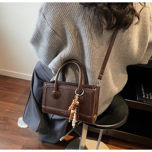 Détail d'un sac à main en cuir marron foncé avec charm en bois et texte élégant gaufré