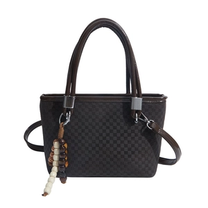 Brown checkerboard pattern bucket bag with leather handles and beaded charm detail
