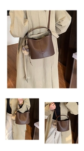 Detail view of brown pebbled bucket bag with plush charm and leopard bow on shoulder strap