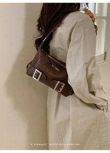 Detail of dark brown retro leather shoulder bag with a silver buckle strap and zip closure