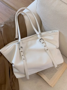 Minimalist white leather tote bag with silver buckles shown in a lifestyle setting