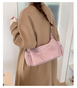 Close-up of pink suede shoulder bag with decorative silver zippers and long pullers