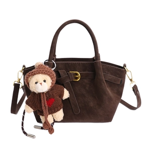 Dark brown suede bucket bag with top handles, gold buckle and plush bear charm