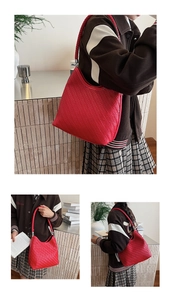 Detail of red woven hobo bag with thick braided strap and silver hardware accents