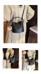Detail of black leather bucket bag with plush pom-pom and leopard print ribbon scarf