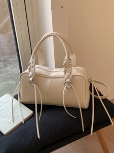 Beige faux leather Boston bag with braided metallic eyelets and long decorative tassels
