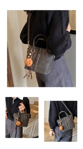 Détail du cabas en daim gris foncé avec breloque en peluche orange et bandoulière réglable
