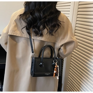 Vue détaillée d'un sac bandoulière noir avec boucles rondes et breloque en perles de bois
