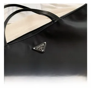 Close-up of triangle metal logo on black nylon tote bag with matte texture detail