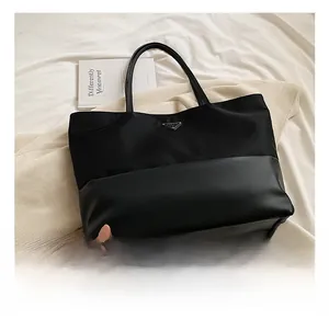Close-up of black nylon tote bag with leather base and triangle logo on white fabric