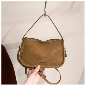 Detail of tan suede crescent bag with silver zipper and Miggiebag leather label