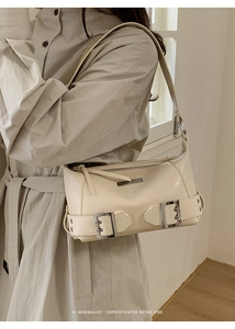 Close-up of cream retro baguette bag with glossy leather texture and metal buckles