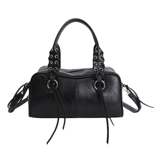 Detail of black Boston bag with woven straps, silver eyelets and long leather tassels