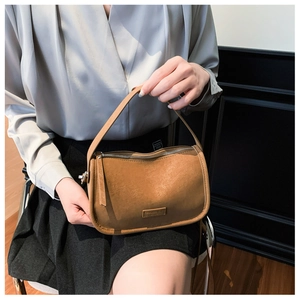 Close-up of brown PU leather handbag with arc zipper and rectangular metal hardware detail