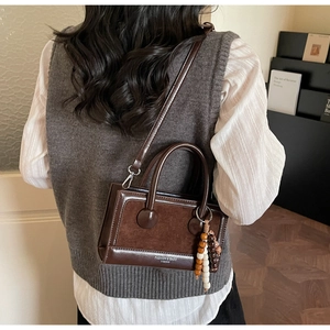 Détail du sac vintage marron foncé avec charme en perles de bois et texture cuir