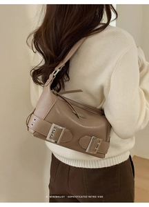 Detail of retro brown shoulder bag with metallic buckle shown on model's shoulder