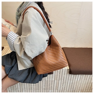 Detail of a brown woven hobo bucket bag showing intricate texture and sturdy strap