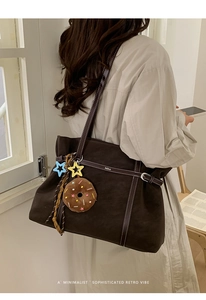 Close-up of brown matte tote bag featuring white stitching and star plush pendant