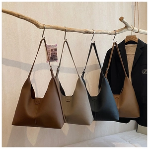 Vier minimalistische Hobo-Taschen in verschiedenen Erdtönen hängen an einem Ast aus Holz