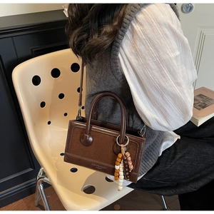 Détail du sac à bandoulière marron vintage avec breloque bohème et empiècements suède