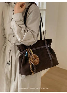 Macro detail of dark brown suede tote bag featuring white contrast stitching and Nika logo