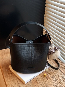 Black lychee leather bucket bag with leopard print pom pom and adjustable shoulder strap
