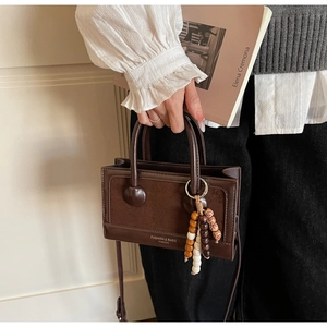 Détail du sac à bandoulière marron vintage avec textures mixtes et perles en bois