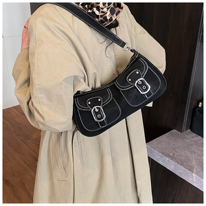 Vintage black underarm bag with white stitching and silver buckles on a khaki trench coat