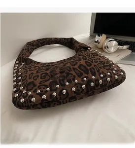 Leopard print hobo bag with silver rivet studs on a stylist desk with headphones