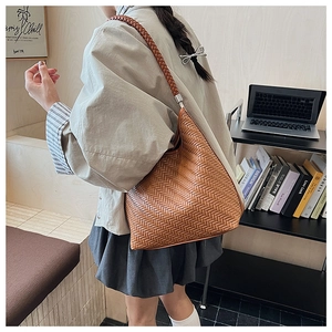 Detailed view of brown woven hobo bag with thick shoulder strap shown in lifestyle setting