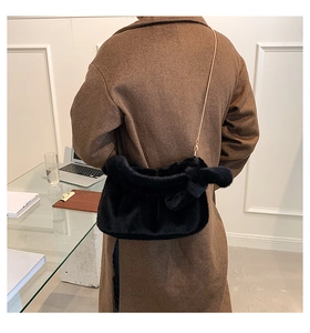 Détail d'un sac à main en peluche noire avec chaîne dorée dans un bureau moderne