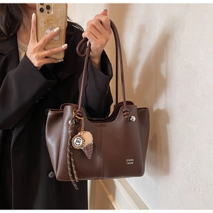 Detail of dark coffee tote bag featuring vertical stitching and a cute plush charm