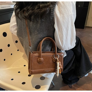 Détail du sac à bandoulière marron vintage avec gland en perles et lettrage de mode
