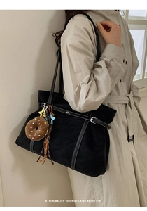 Detail of black matte tote bag with contrast white stitching and cute donut charm