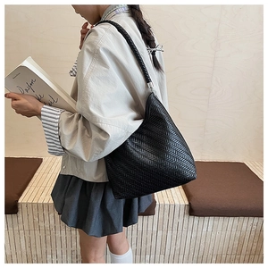 Detailed view of black woven hobo bag showing intricate herringbone texture and strap