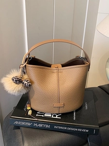 Chic tan leathery bucket bag with luxury faux fur charm on interior design book