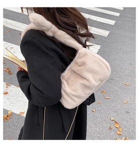 Gros plan d'un sac à bandoulière plissé en peluche beige doux porté dans une rue urbaine