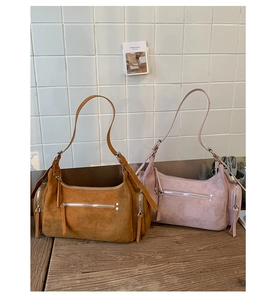 Détails de deux sacs à bandoulière en suède avec fermetures éclair et rivets en métal