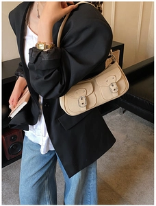 Close-up of cream leather underarm bag with double front pockets on a model in a blazer