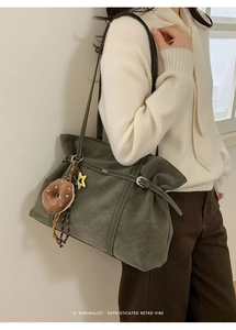 Close-up of minimalist olive green suede tote bag with decorative strap and star charm