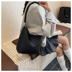 Detail of black woven bucket bag showing intricate PU leather texture and metal buckle