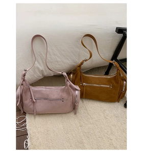 Détail de sacs à bandoulière en daim rose et marron avec fermetures éclair argentées