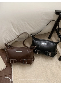 Close-up of retro minimalist baguette bags in brown and black with metal hardware details