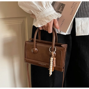 Gros plan du sac à main vintage marron avec un détail de breloque en perles bohèmes colorées