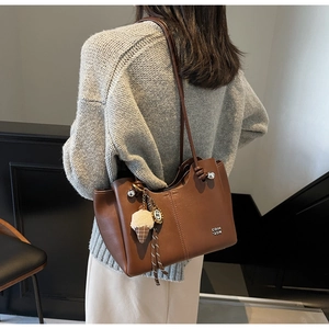 Close-up of brown vintage tote bag with plush ice cream charm and textured faux leather