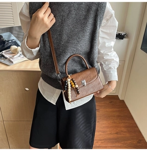 Retro brown leather crossbody bag with colorful wooden bead charm and metal lock closure