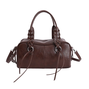 Dark brown leather Boston bag with metallic eyelets, braided handles, and long tassels
