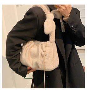 Détail du sac nuage en fausse fourrure crème avec chaîne dorée porté sur un costume